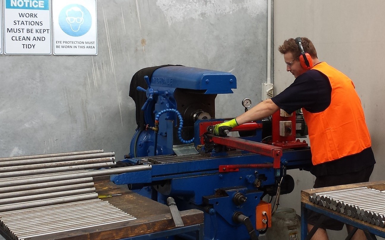 Junger Mann arbeitet an einer Maschine mit Metallrohren